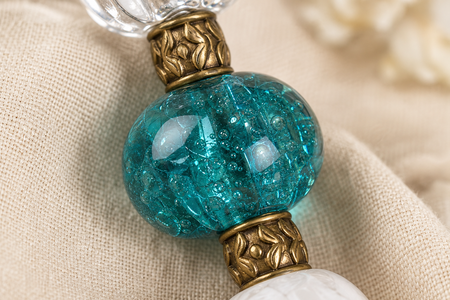 Close-up of a teal crackle glass bead and antique brass spacers